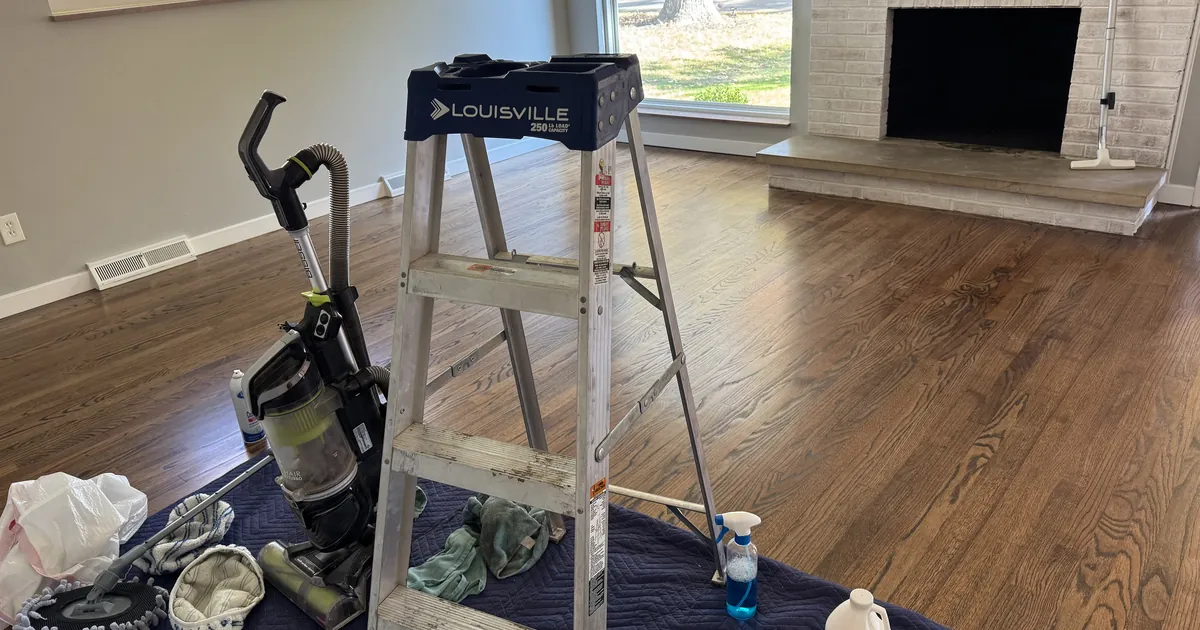 Freshly renovated St. Louis living room with refinished hardwood floors, a ladder and cleaning equipment set up for the final clean