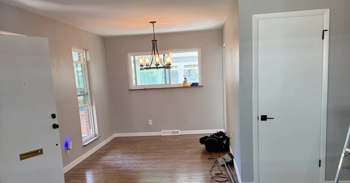 Empty dining room with a chandelier and polished hardwood floors, ready for holiday guests