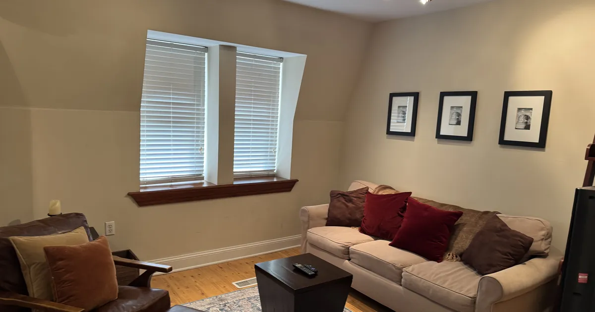 Clean living room with framed pictures, a sofa and hardwood floors