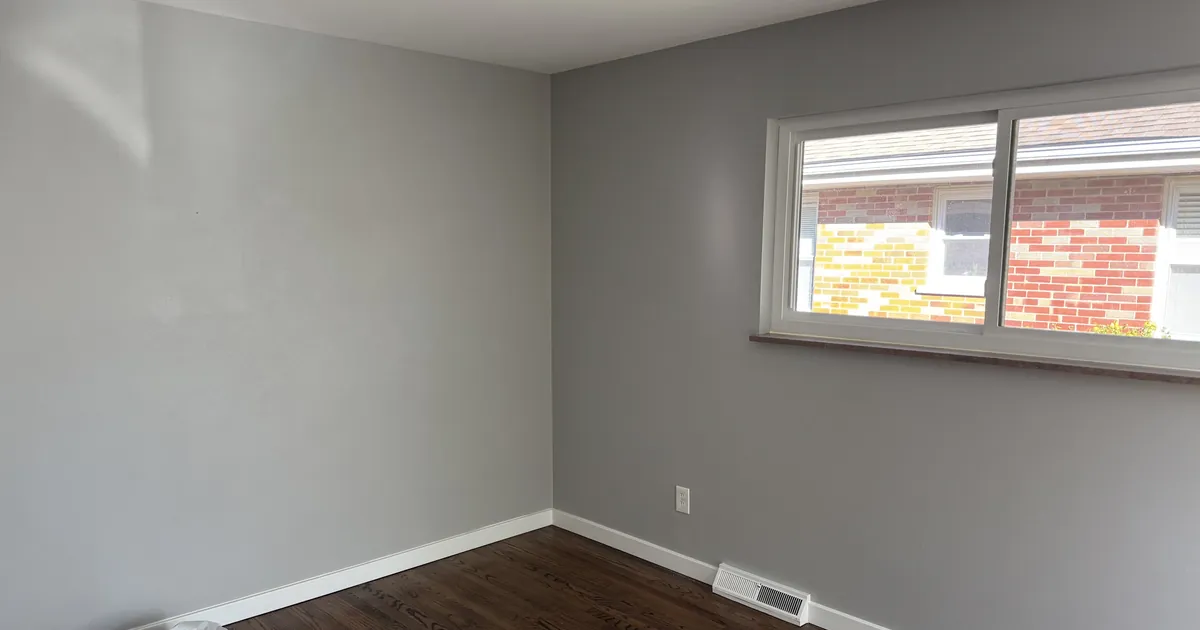 Empty room in a newer home with fresh gray walls and a clean window before move-in