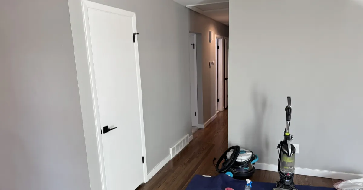Renovated hallway with new white doors, hardwood floors and cleaning equipment on a protective mat