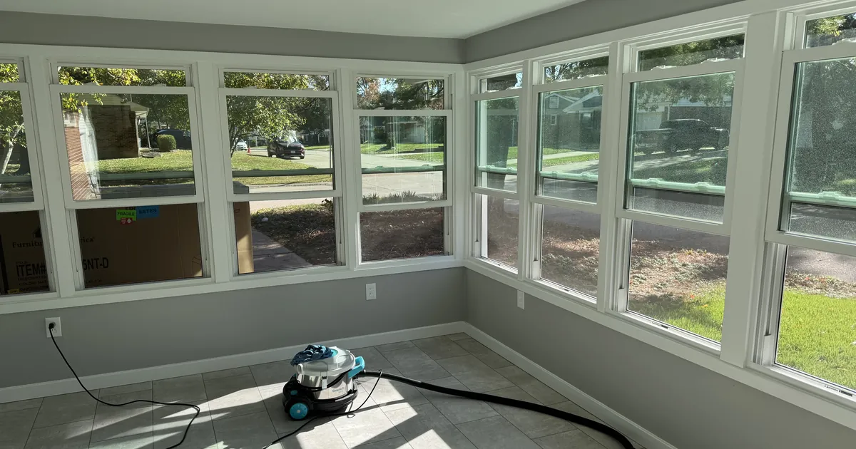 Sunroom lined with windows, with a vacuum on the tile floor during window cleaning