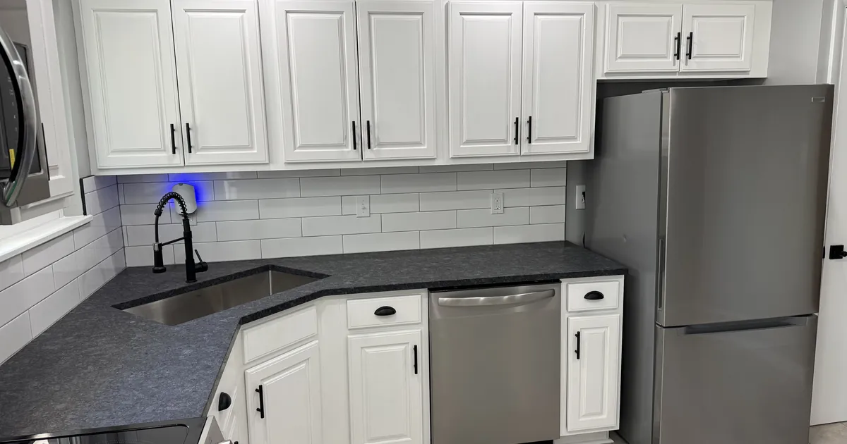 Stainless steel refrigerator and dishwasher in a clean white kitchen