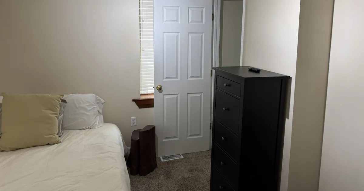 Bedroom with a freshly made bed and tidy dresser after a house cleaning